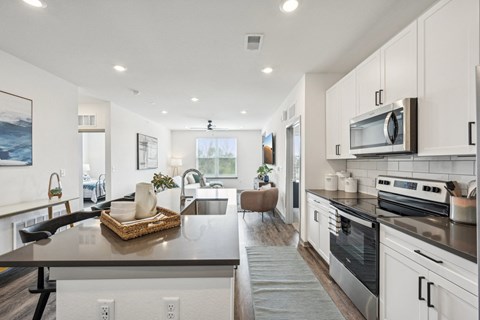 an open kitchen and living room with a large counter top at The Quarry Luxury Apartment Homes, Fort Collins, CO